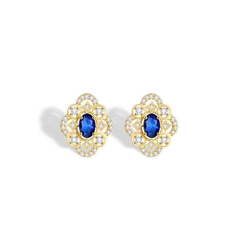 Blue floral stud earrings with gold-tone outlines and clear accents on a white background